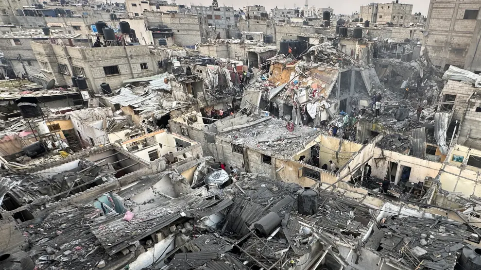 La gente busca entre los escombros de los edificios dañados tras un ataque aéreo israelí contra casas palestinas, en medio del conflicto en curso entre Israel y el grupo islamista palestino Hamas, en Rafah