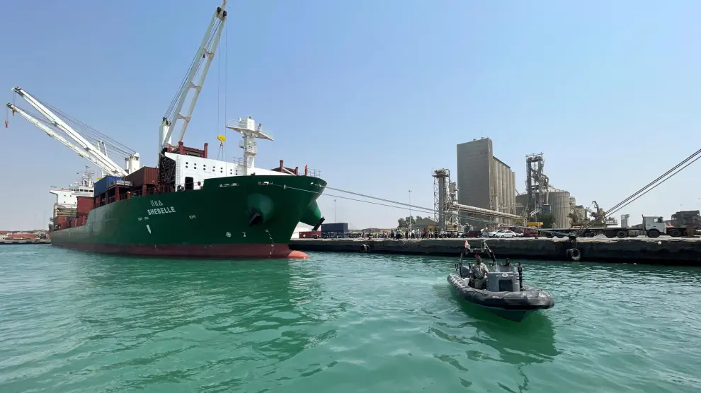 Un barco guardacostas pasa junto a un buque portacontenedores comercial atracado en el puerto de Hodeidah, en el Mar Rojo, controlado por los hutíes