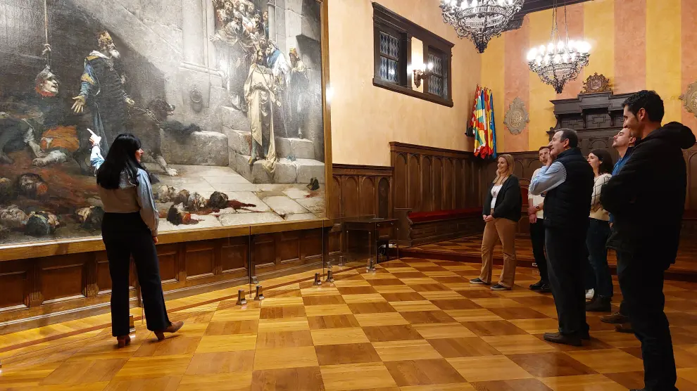 La alcaldesa de Huesca, Lorena Orduna, explica el cuadro de La Campana a los representantes de LiveNLearn.