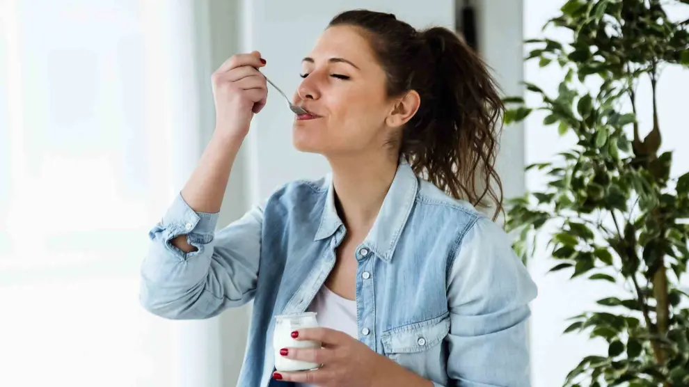 Una mujer comiendo un yogur.