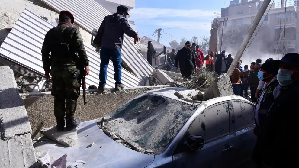 Un grupo de soldados revisa un coche dañado por el bombardeo de un edificio en Damasco, Siria