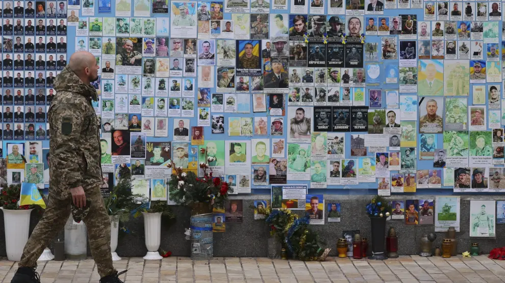 Un soldado pasa por una pared con las fotos de militares caídos en la guerra con Rusia.