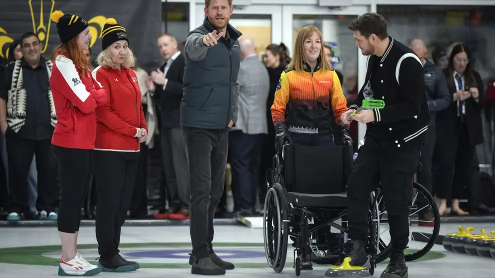 Prince Harry, the Duke of Sussex, jokingly warns photographers to move out of the way as singer Michael Buble, right, prepares to try wheelchair curling during an Invictus Games training camp in Vancouver, British Columbia, Friday, Feb. 16, 2024. (Darryl Dyck/The Canadian Press via AP)