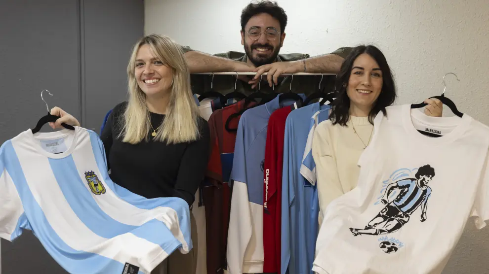 De izquierda a derecha, los aragoneses María Faci, Iván Royo y Alexandra Fernández, fundadores del estudio Deofis, con algunos ejemplos de sus diseños para la nueva marca Diego Maradona.