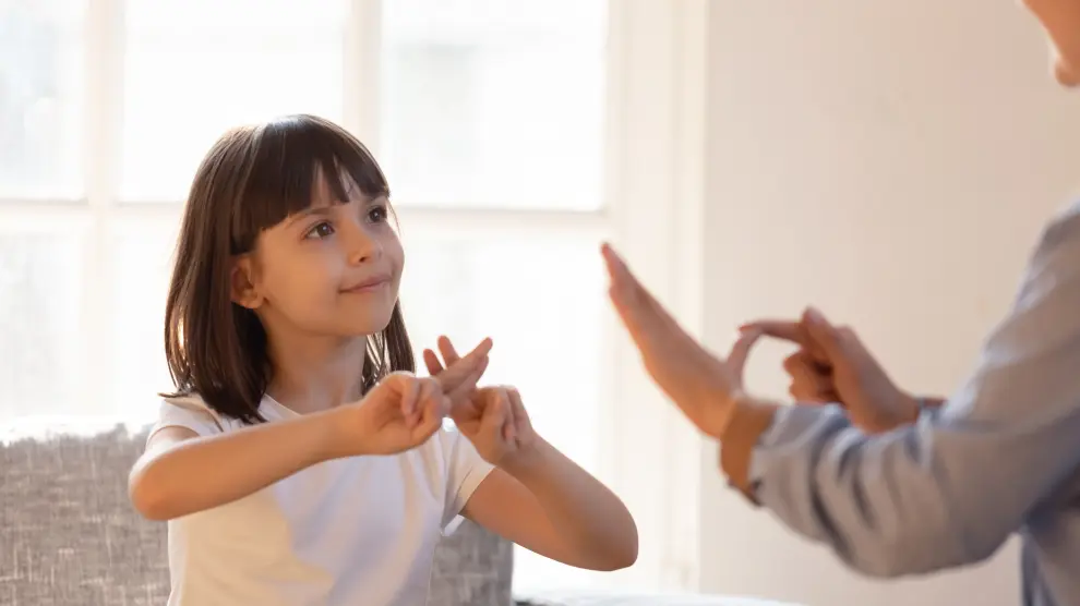 Una niña interactúa con otra persona a través de la lengua de signos.
