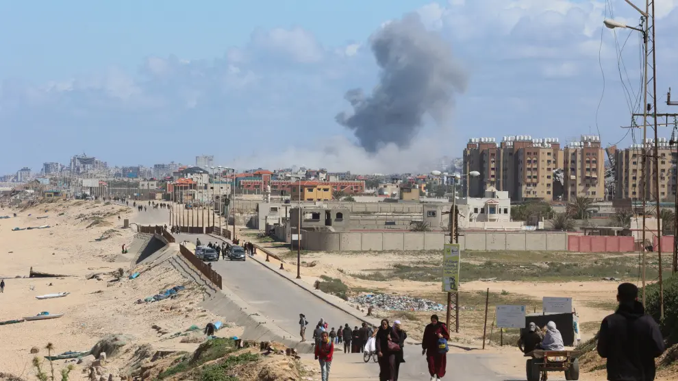 El humo se eleva tras un ataque israelí mientras los palestinos que huyen del norte de Gaza debido a la ofensiva militar de Israel se desplazan hacia el sur, en la franja central de Gaza.