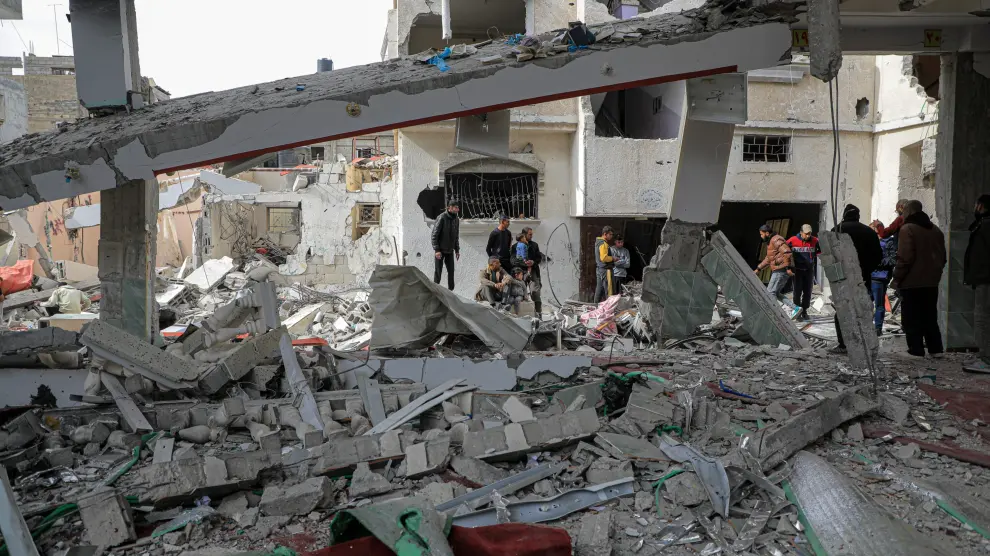 Palestinos entre los restos de edificios destruidos por los bombardeos del Ejército de Israel contra la ciudad de Rafá, en el sur de la Franja de Gaza.