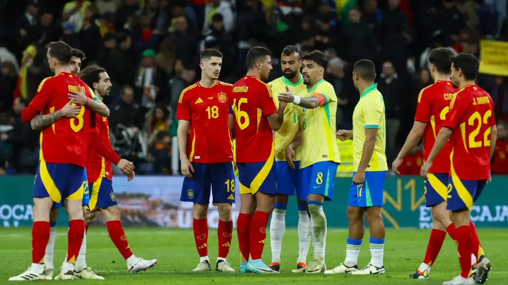 El centrocampista de la selección brasileña Lucas Paquetá (c-d) habla con Rodri, de España, durante el partido amistoso que las selecciones nacionales de fútbol de España y Brasil disputan hoy martes en el estadio Santiago Bernabéu, en Madrid.