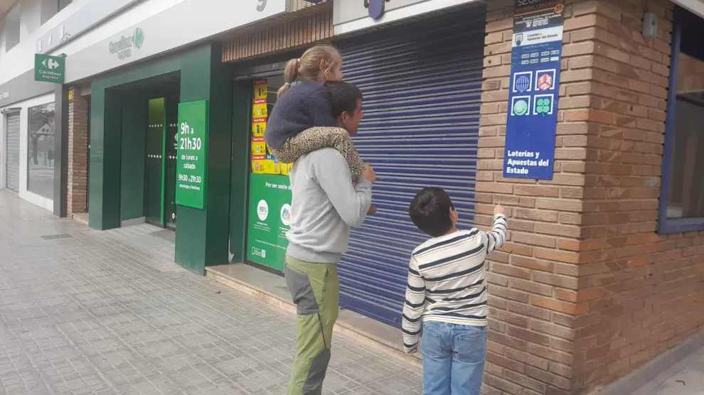 Una familia se detiene ante la Administración de Lotería de la Avenida de Sagunto de Teruel tras conocer que el establecimiento vendió el número premiado.