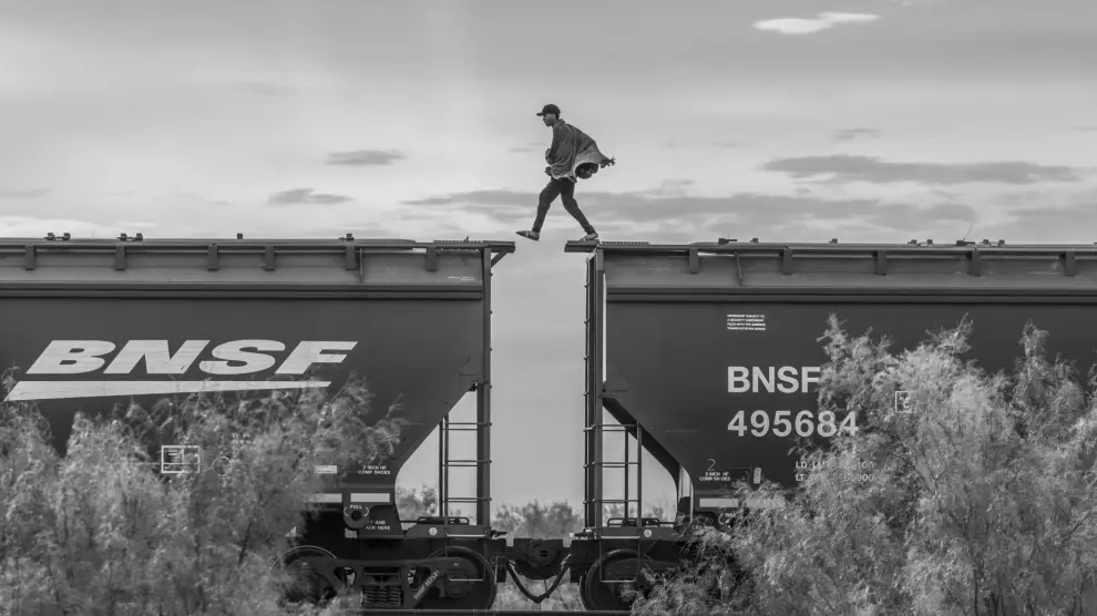 This image provided by World Press Photo and taken by Alejandro Cegarra for The New Times/Bloomberg is part of a series titled The Two Walls which won the World Press Photo Long-Term Project Award and shows a migrant walking atop a freight train known as "The Beast." Migrants and asylum seekers lacking the financial resources to pay a smuggler often resort to using cargo trains to reach the United States border. This mode of transportation is very dangerous; over the years, hundreds have fallen onto the tracks and have been killed or maimed. Piedras Negras, Mexico, 8 October 2023. (Alejandro Cegarra/The New York Times/Bloomberg/World Press Photo via AP)