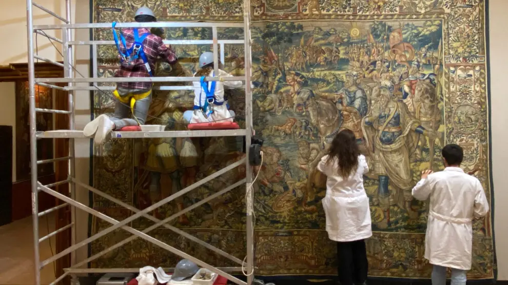 Dos restauradores trabajan en un tapiz elaborado en Bruselas en el siglo XVI que se expone en el Museo Diocesano de Albarracín.
