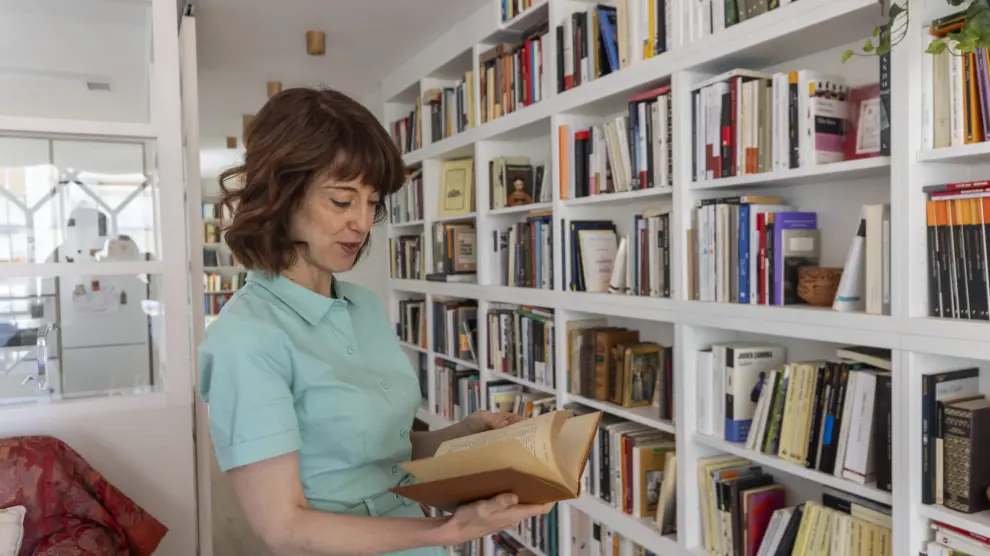 Irene Vallejo, premio de las Letras Aragonesas, hojeando un libro de su biblioteca en su domicilio zaragozano.