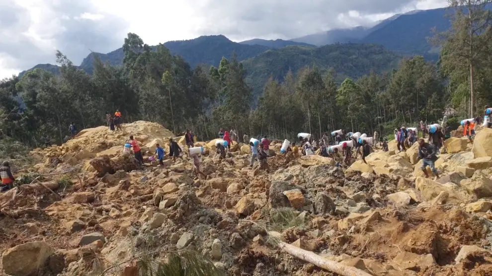 Personas cargando bolsas después de un deslizamiento de tierra en la provincia de Enga, Papúa Nueva Guinea