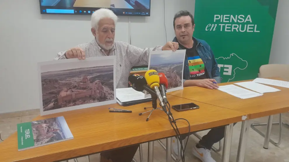 Manuel Gimeno y Jesús Villamón, de Teruel Existe, muestran fotografías de cómo cambiará el entorno del castillo de Peracense por la proximidad de aerogeneradores.