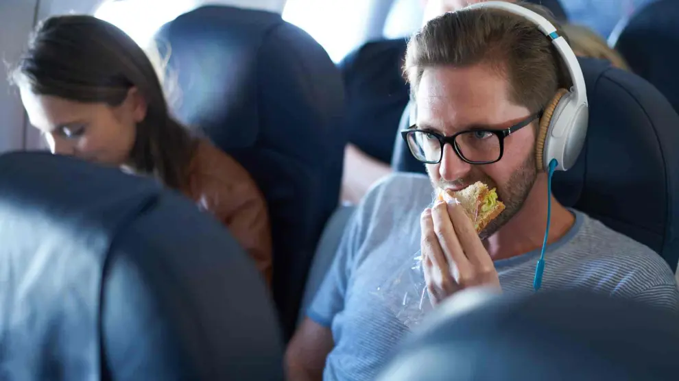 Hombre almorzando durante un viaje en avión.