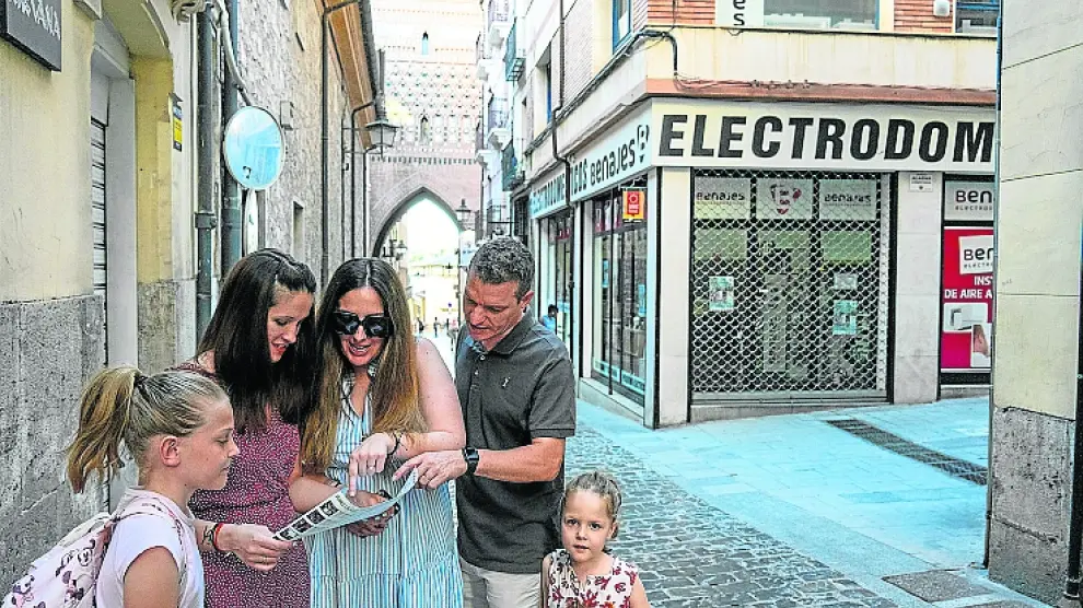 Una familia consulta un folleto en una calle de Teruel