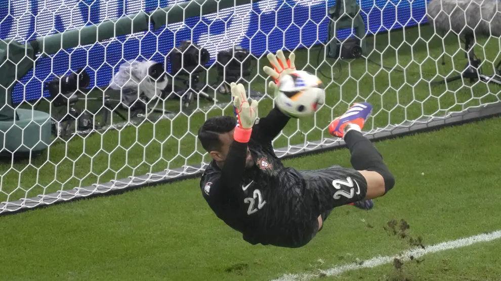 Portugal's goalkeeper Diogo Costa saves the ball during penalties of a round of sixteen match between Portugal and Slovenia at the Euro 2024 soccer tournament in Frankfurt, Germany, Monday, July 1, 2024. (AP Photo/Michael Probst)