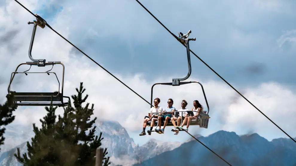 Cuatro excursionistas en el telesilla El Molino de Cerler, que sube hasta 2000 metros de altitud y que permite además portar bicicletas.