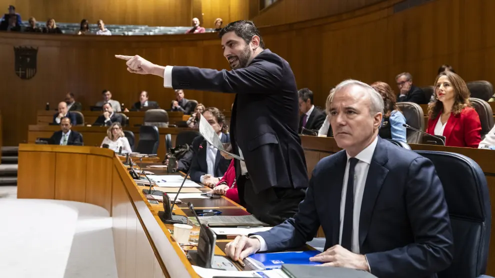 Alejandro Nolasco, con Jorge Azcón a la derecha, se dirige a la oposición para rechazar las acusaciones de xenofobia que recibió durante el pleno