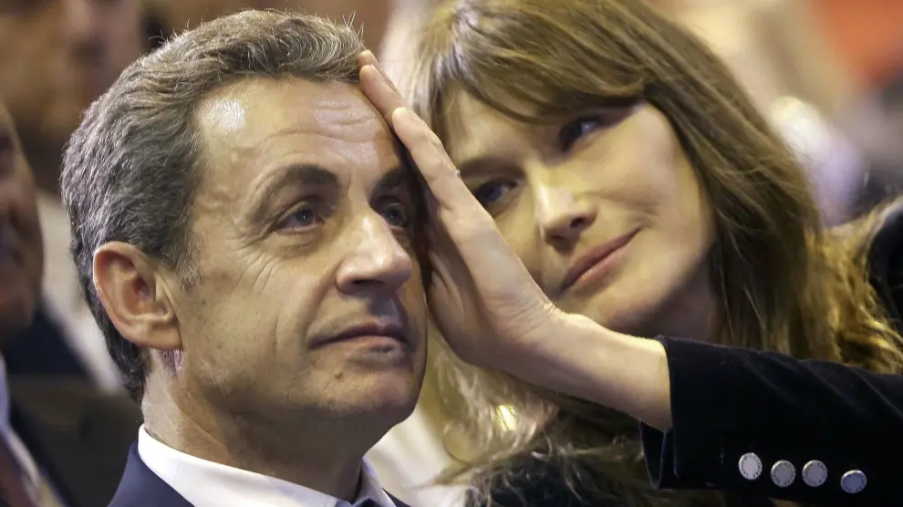 FILE - In this Thursday, Oct. 27, 2016 file picture, Carla Bruni-Sarkozy caresses the brow of her husband, the former French President and candidate for France's conservative presidential primary, Nicolas Sarkozy, during a campaign meeting in Marseille, southern France. Former first lady Carla Bruni-Sarkozy was given preliminary charges Tuesday, July 9, 2024, and placed under judicial supervision for alleged involvement in efforts to pressure a witness who accused ex-President Nicolas Sarkozy of receiving illegal campaign financing from Libya. (AP Photo/Claude Paris, File)
