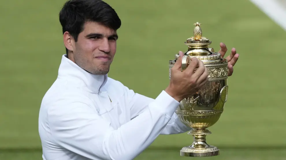 Carlos Alcaraz of Spain smiles as he holds up his trophy for the photographers after defeating Novak Djokovic of Serbia in the men's singles final at the Wimbledon tennis championships in London, Sunday, July 14, 2024. (AP Photo/Mosa'ab Elshamy)