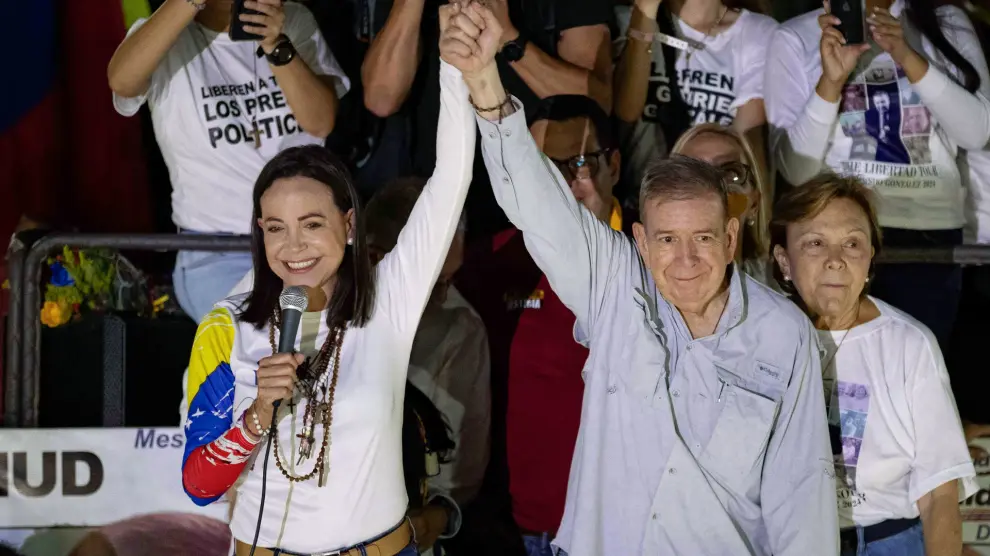 AME4966. CARACAS (VENEZUELA), 25/07/2024.- La líder opositora venezolana, María Corina Machado (i), y el candidato a la presidencia de Venezuela, Edmundo González Urrutia (c), saludan a simpatizantes en el cierre de campaña de González Urrutia, este jueves, en Caracas (Venezuela). González Urrutia pidió a los venezolanos, en un acto de clausura de la campaña electoral, votar el domingo para comenzar el camino de la "reconciliación nacional". EFE/ Ronald Peña R.