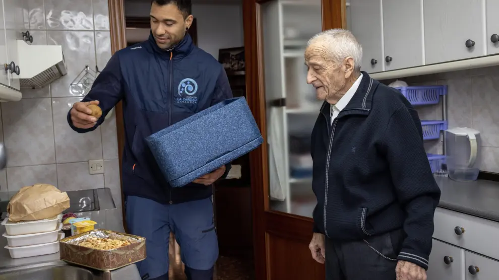 Un trabajador del programa de la Fundación la Caridad entrega comida a una persona mayor en su domicilio.