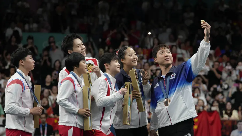 South Korea's Lim Jonghoon, right, takes a selfie with North Korea's Ri Jong-sik, left, and Kim Kum Yong, second left, China's Wang Chuqin, background, and Sun Yingsha, center, and his teammate Shin Yubin, right, during the medal ceremony at the 2024 Summer Olympics, Tuesday, July 30, 2024, in Paris, France. (AP Photo/Petros Giannakouris) Associated Press/LaPresse