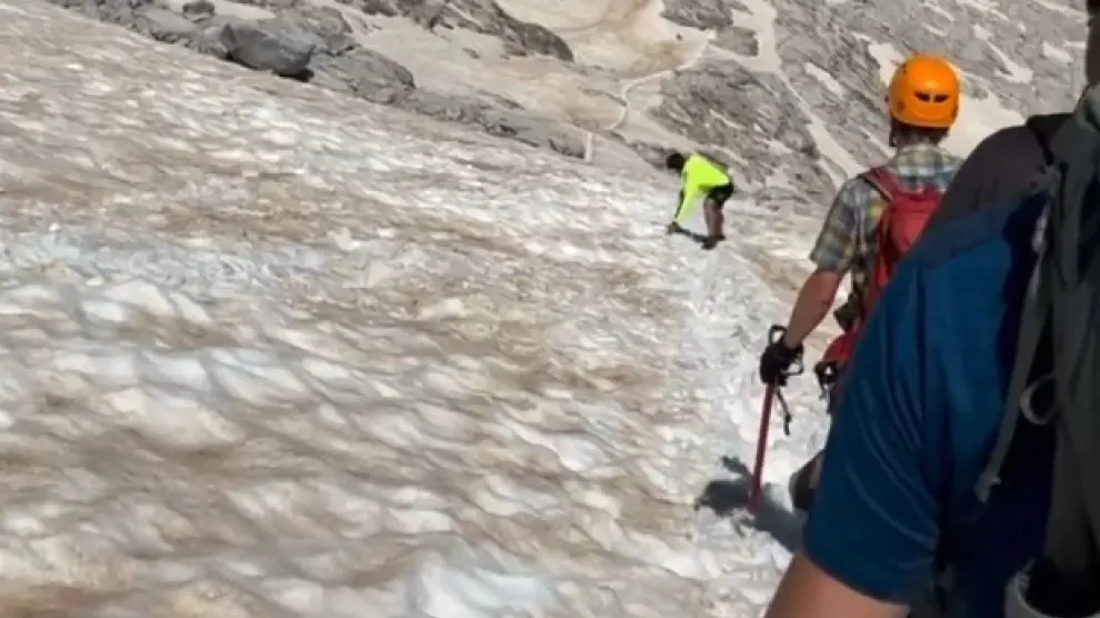 Al fondo, el montañero descendiendo el glaciar del Aneto con la única ayuda de un pilolet, pero sin el resto del material necesario.