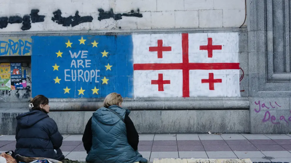 Imagen de archivo de dos mujeres frente a murales de la Unión Europea y la bandera georgiana en Tbilisi, Georgia