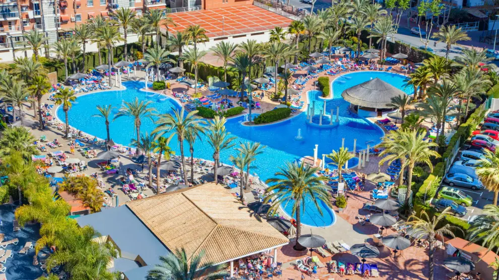 Una piscina estilo lago con una fuente y zonas de hidromasaje.