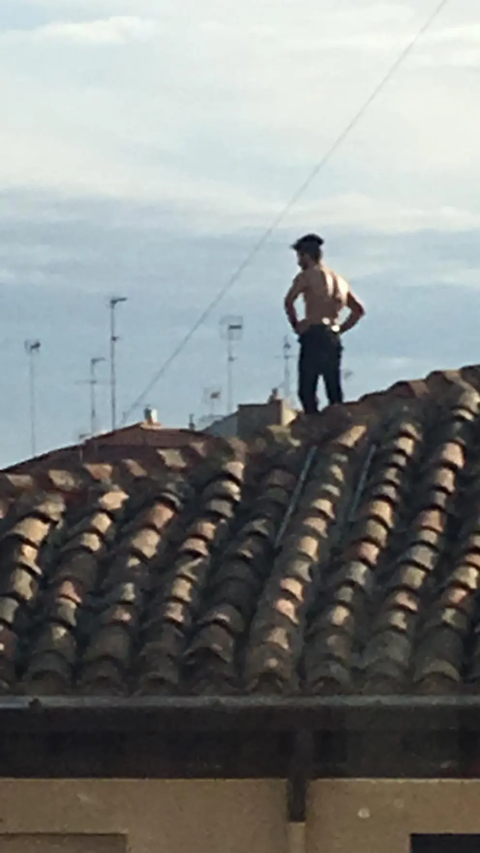 no de los jóvenes encaramado al tejado de un edificio okupa en la calle Pignatelli número 67 de Zaragoza.