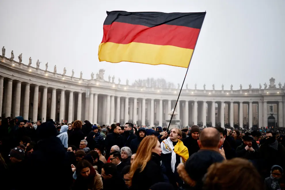 Un asistente al funeral del papa emérito sostiene la bandera de Alemania.
