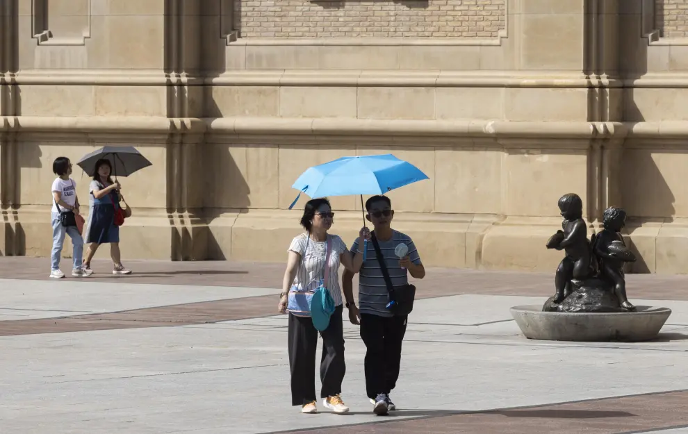 Varias personas paseando por la plaza del Pilar durante un día de calor extremo.