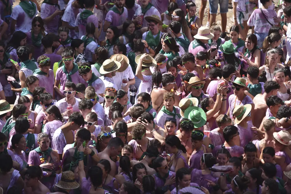 El chupinazo de Huesca es una marea morada de jóvenes con las camisetas blancas teñidas por el vino.