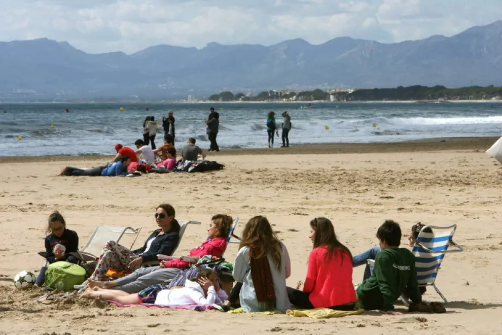 Varias personas intentan tomar hoy el sol en la Playa de Levante de Salou