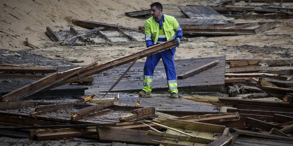 Un operario municipal recoge maderas en la Playa de los Peligros de Santander