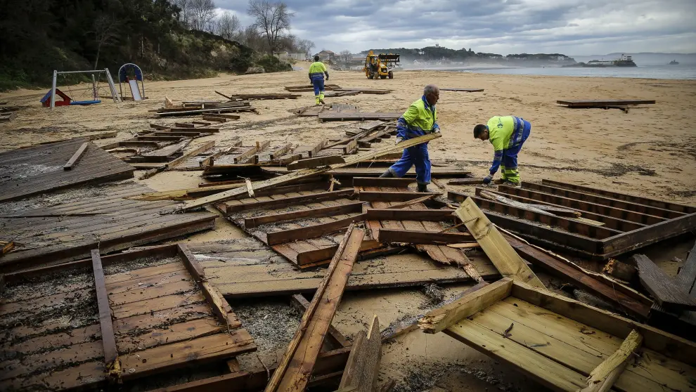 Operarios municipales recogen maderas en la Playa de los Peligros de Santander