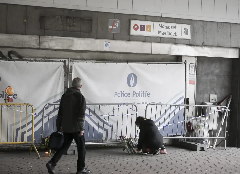 Una mujer deja un ramo de flores ante la estación de metro de Maalbeek, en Bruselas