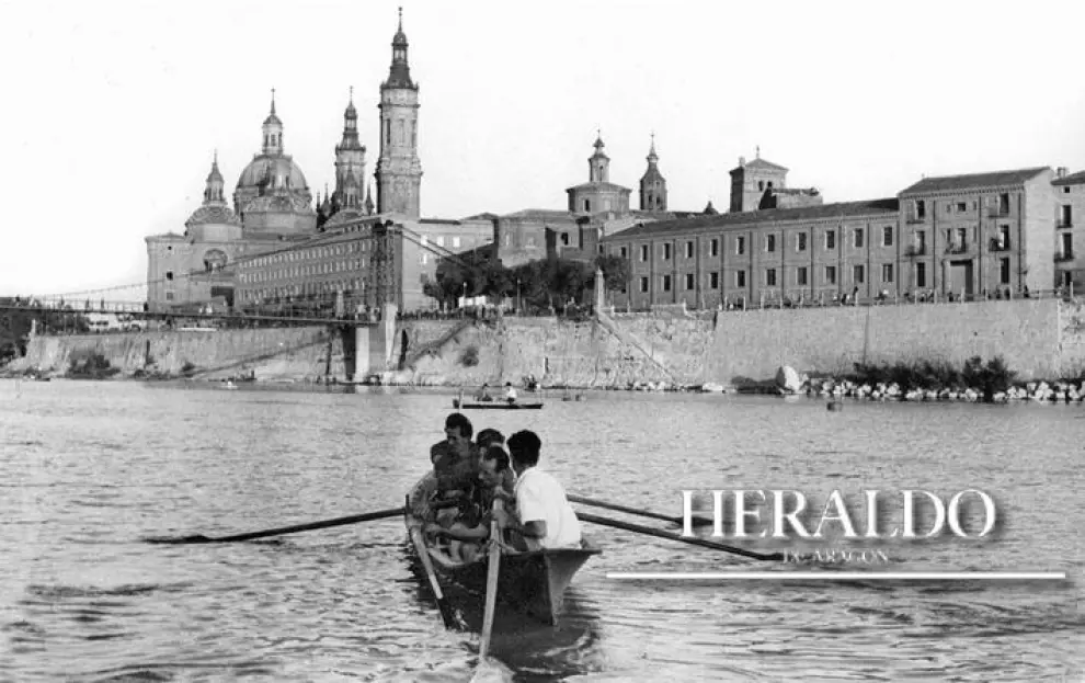 Un grupo de remeros en el río Ebro al salir del embarcadero para un entrenamiento en julio de 1948. Al fondo, la basílica del Pilar incompleta, ya que faltaban dos torres -San Francisco de Borja y Santa Leonor-, que comenzaron a levantarse a partir de 1949.