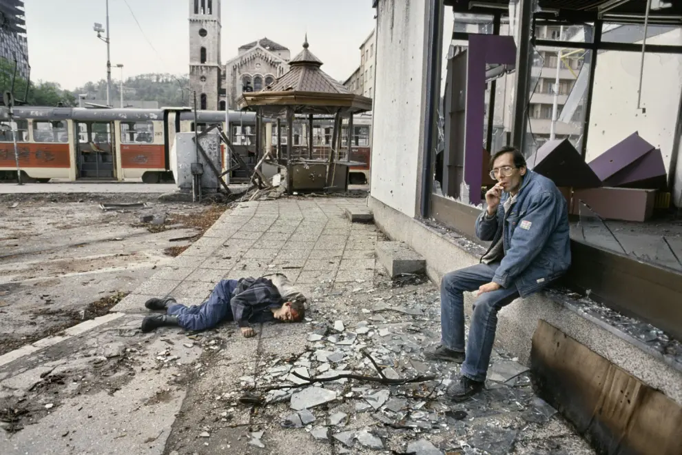 Sarajevo, junio de 1992. Un hombre fuma al lado de un joven asesinado por un francotirador.