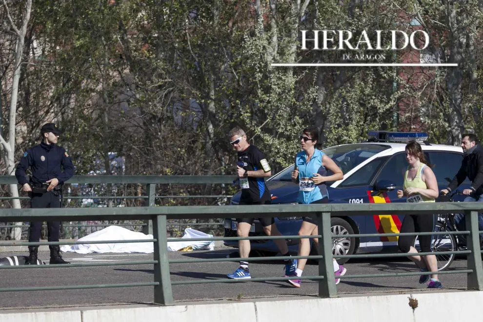 La muerte del médico y cofrade Juan Murillo tiñó de luto el XX Medio Maratón Ibercaja-Ciudad de Zaragoza el 12 de marzo. En la imagen, varios corredores pasan junto a la víctima, que se desplomó cuando había recorrido dos km.