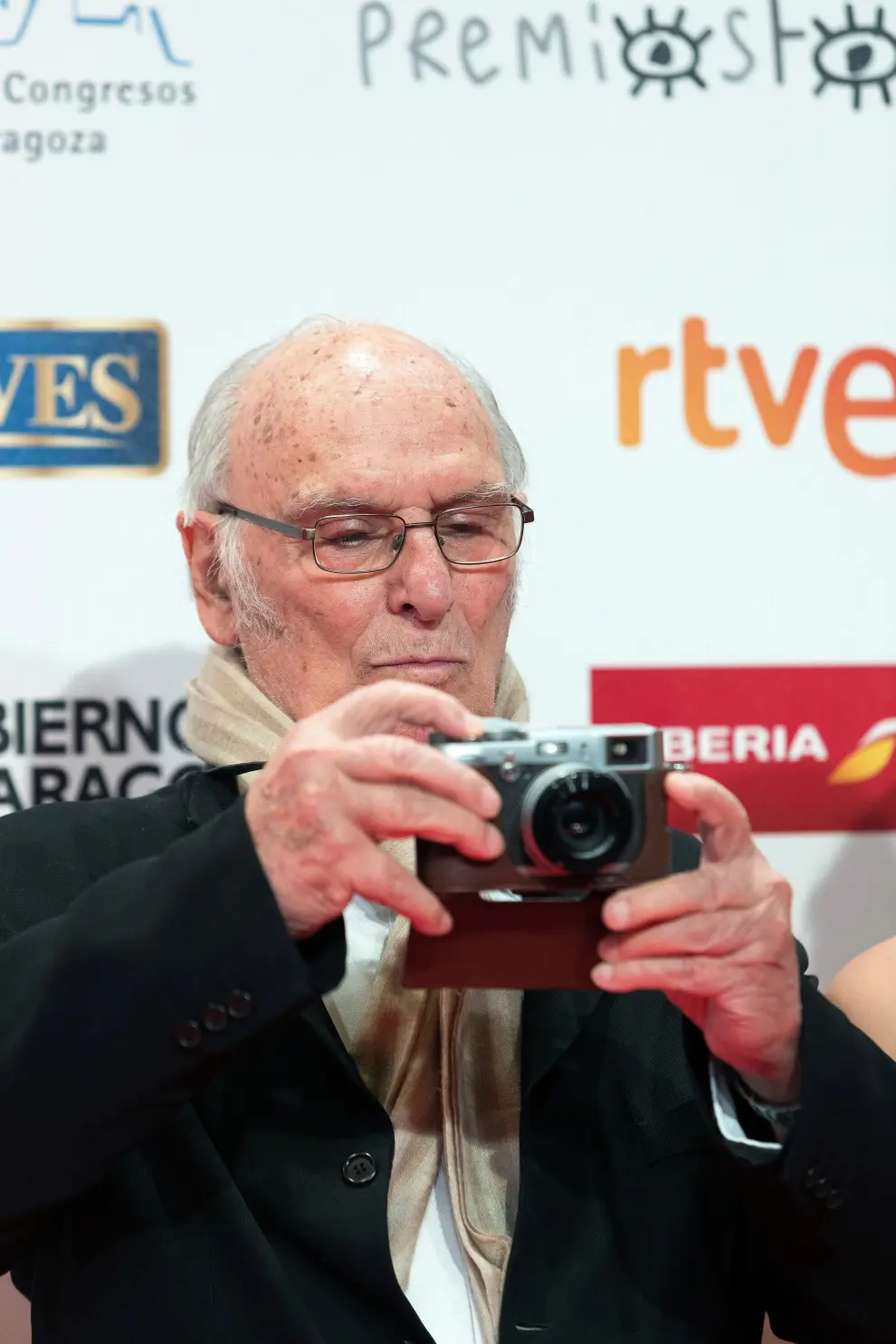 El cineasta Carlos Saura toma una fotografía a su llegada a la gala de entrega de los Premios Forqué.
