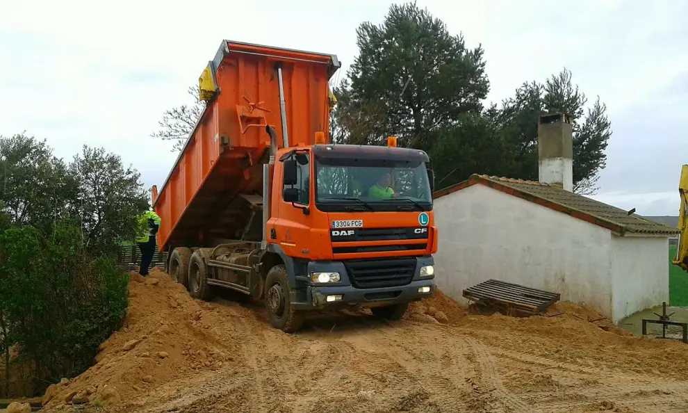 Cuatro camiones, una motoniveladora y una retroexcavadora de la Diputación de Zaragoza trabajan en Quinto para reforzar y mejorar las defensas que protegen el casco urbano de la riada del Ebro.