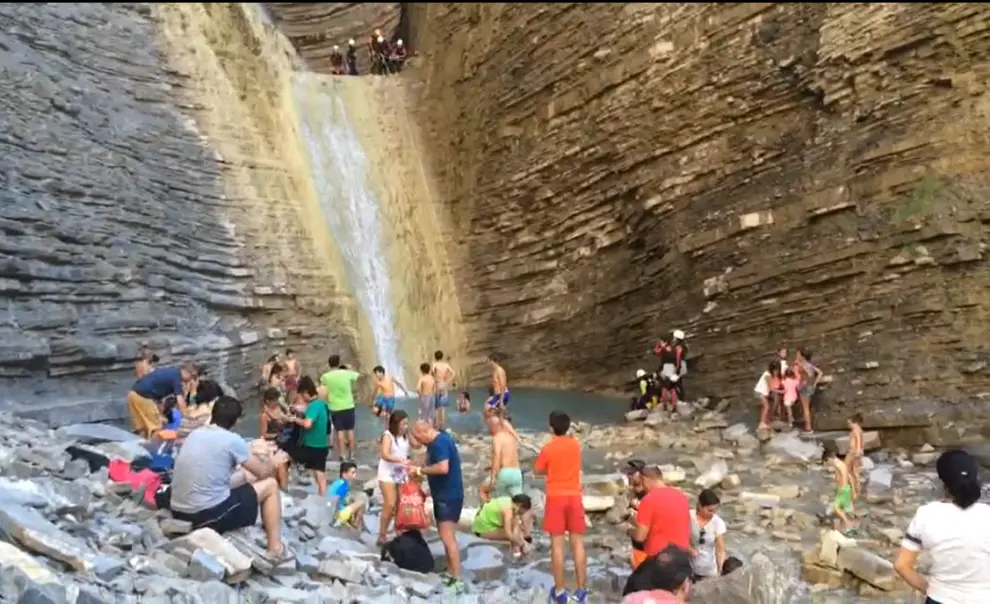 Imagen de la cascada de Orós Bajo repleta de bañistas y barranquistas