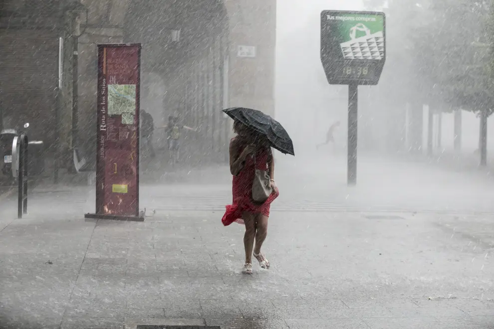 Una mujer trata de resguardarse de la lluvia en el Paseo de la Independencia