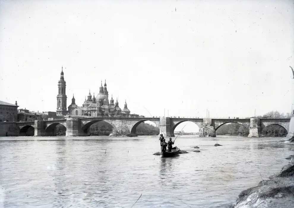 Unos pescadores surcan las aguas del Ebro con la Basílica y sus dos torres en la década de los 20