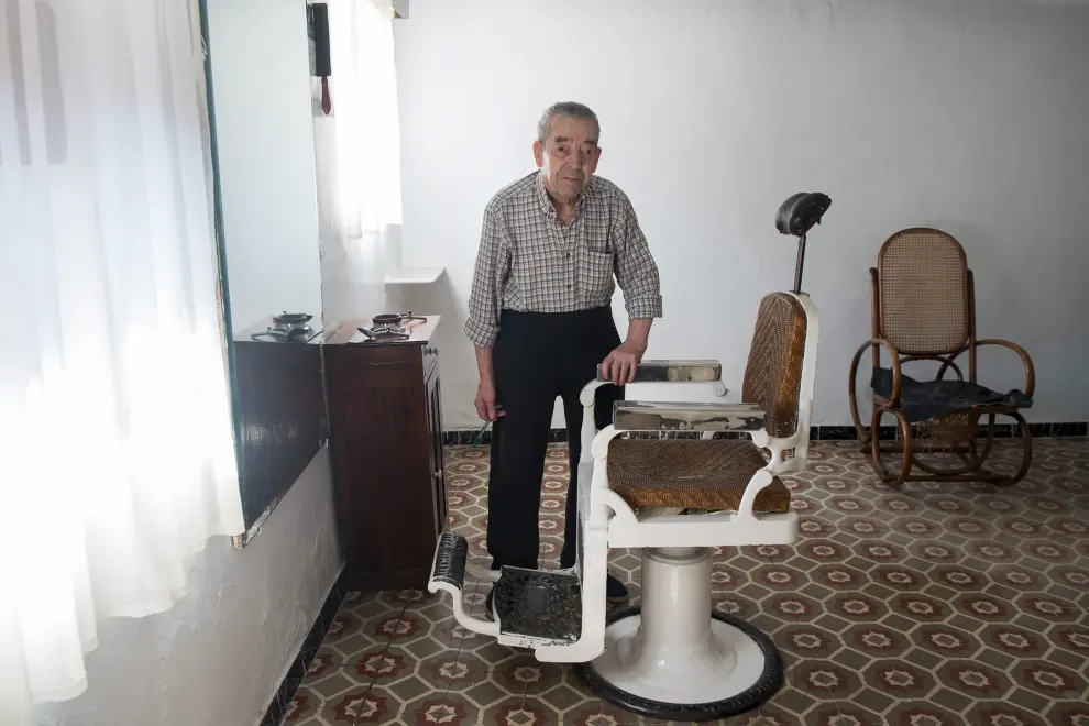 Fernando Artigot, el barbero del pueblo, junto con su antigua silla en la barbería