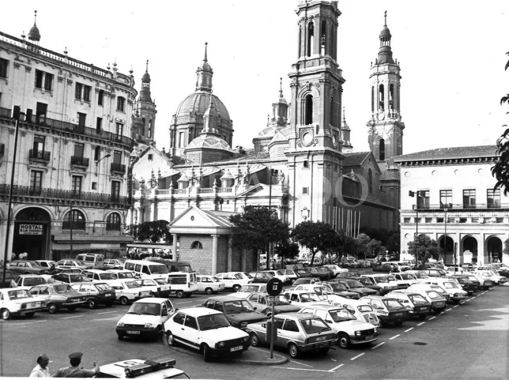 En esta atípica foto de la plaza del Pilar con coches aparcados de finales de los ochenta, podemos ver también el templete de la oficina municpal de turismo