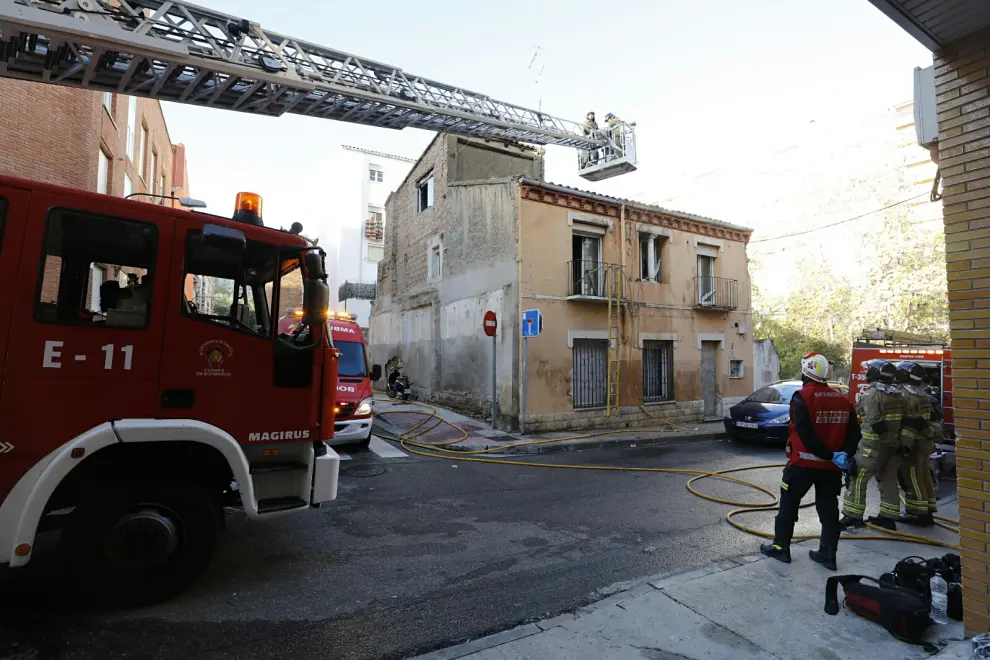 Bomberos de Zaragoza trabajan para sofocar el incendio en una casa con okupas junto al río Huerva